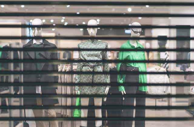 Clothing mannequins behind the closed shutters of a store