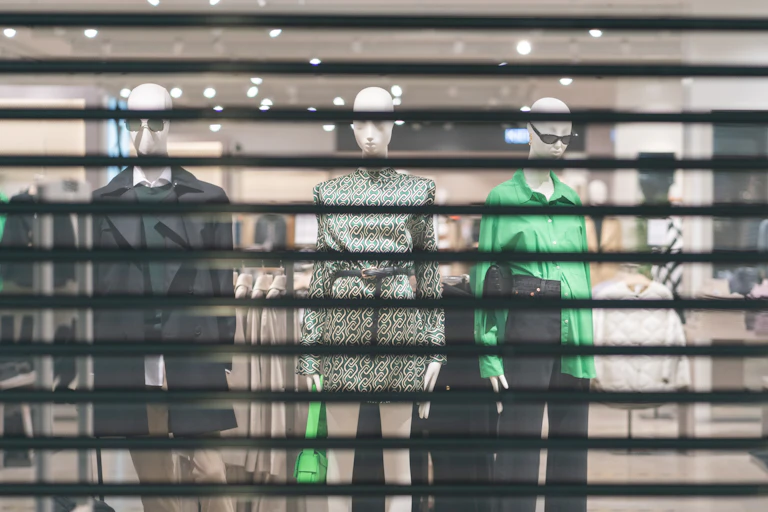 Clothing mannequins behind the closed shutters of a store