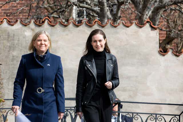 Two women, one wearing a blue coat and black jacket.