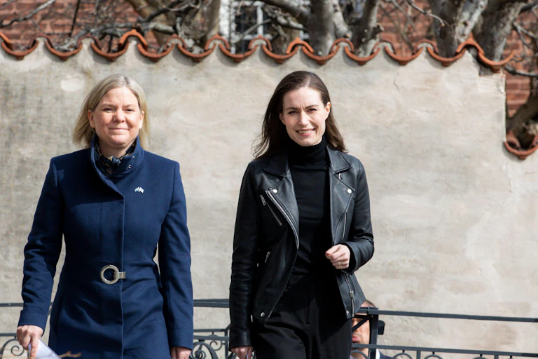 Two women, one wearing a blue coat and black jacket.