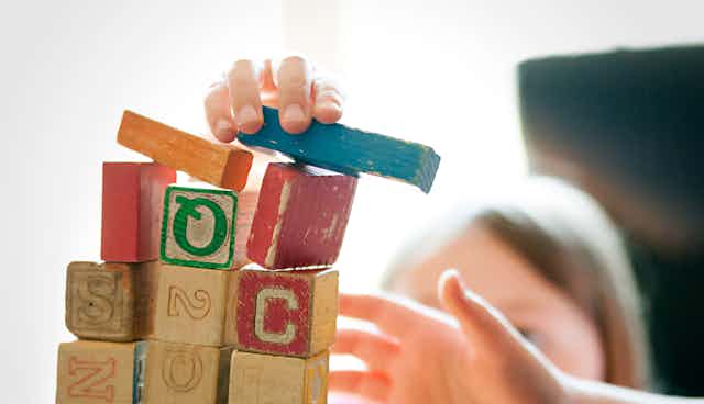 Children play with well-word wooden blocks.