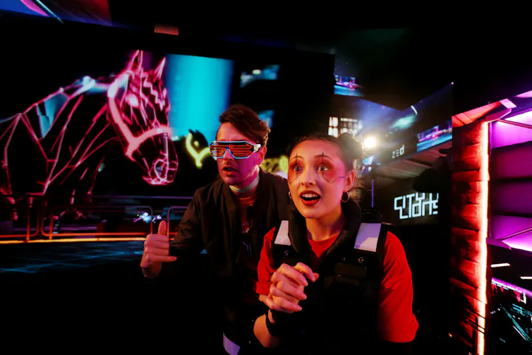 Two people stand in front of a screen with a digital image of a horse.