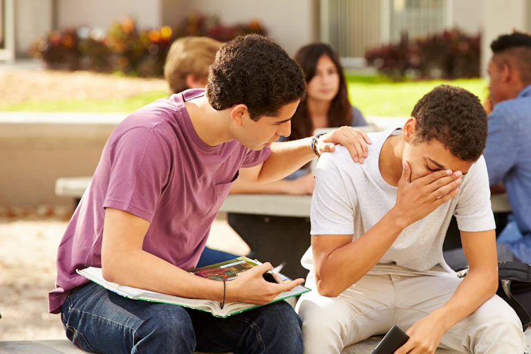 A male student comforts a distressed classmate