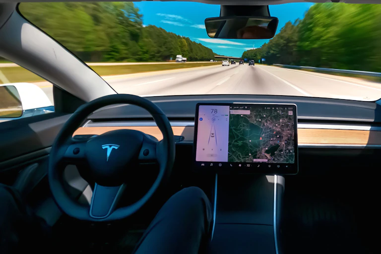 Photo showing view from the front seat of a car driving on a freeway with nobody at the wheel.