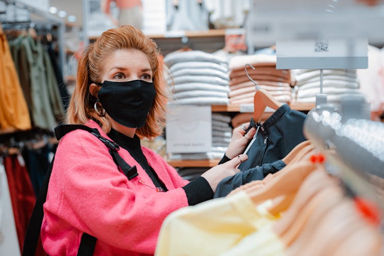 Woman in a mask shops for clothes.