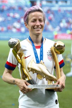 US women's team captain Megan Rapinoe holding the women's world cup trophy.
