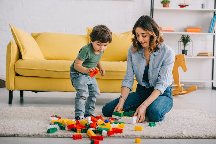 A mother and child play with Lego on the floor