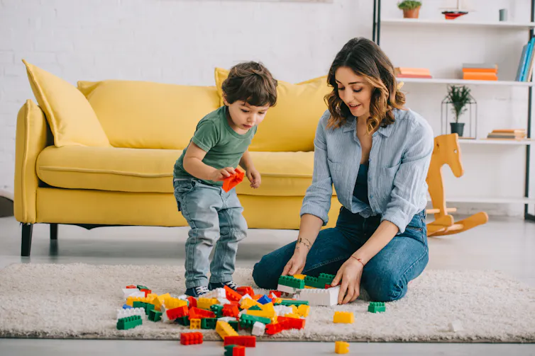 A mother and child play with Lego on the floor