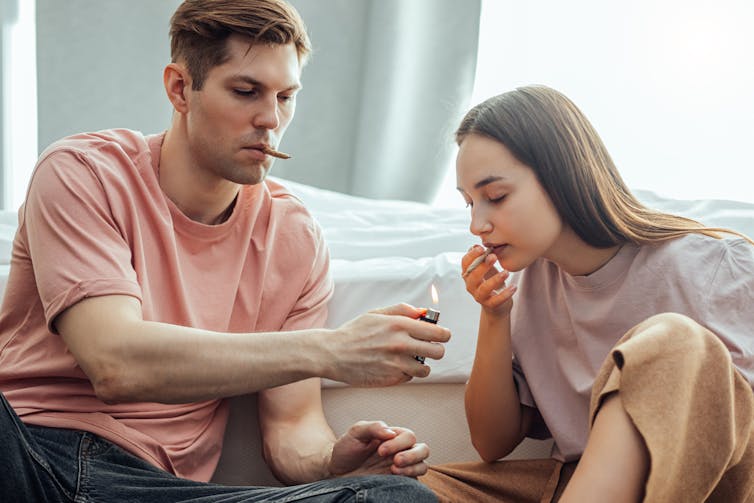 Un jeune couple tranquillement installé s’allume une cigarette chacun