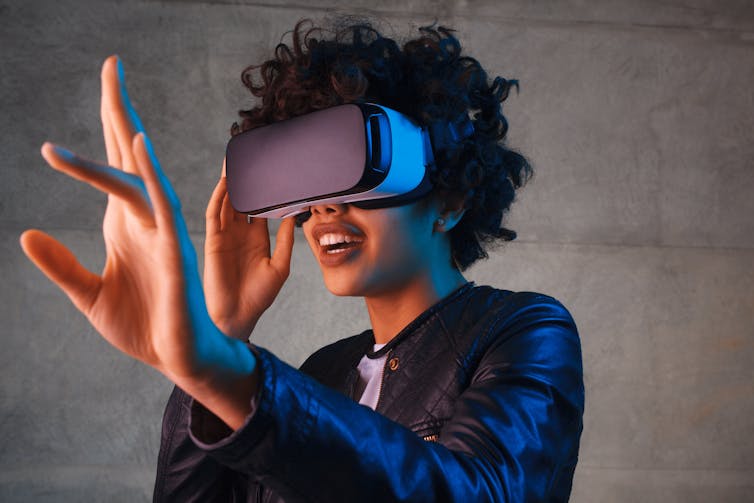 A woman who wears a VR headset with a stretched hand