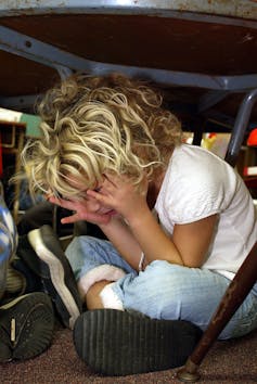 School children hide under their desks as part of a lockdown drill.