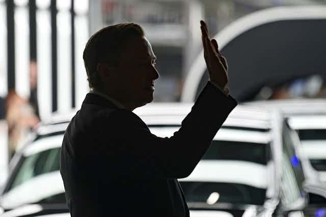 Elon Musk is silhouetted as he waves