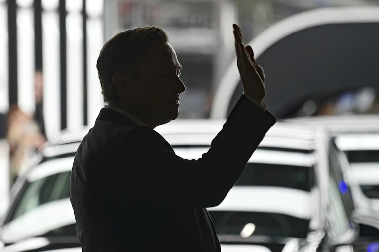 Elon Musk is silhouetted as he waves