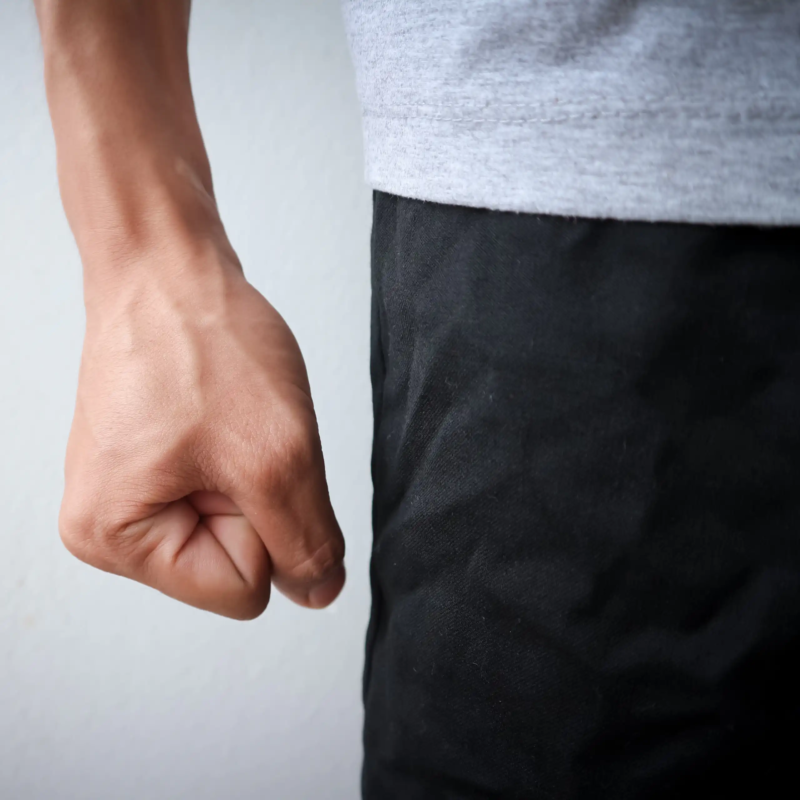 Le poing d'un homme est serré contre sa cuisse.
