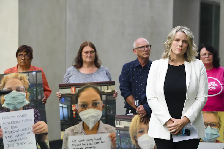 woman stands to speak with health workers standing behind