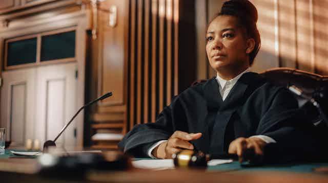 A female judge, dressed in black robe, is about to render a decision in the courtroom.