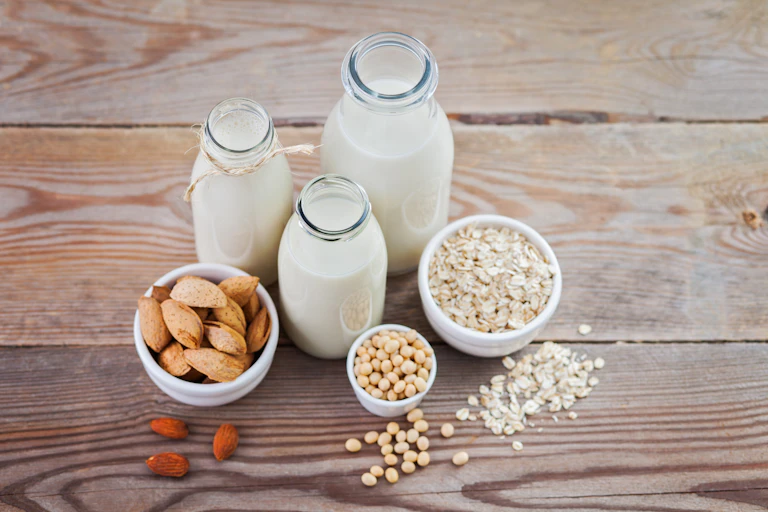 Three glass bottles filled with almond, soya and oat milks.
