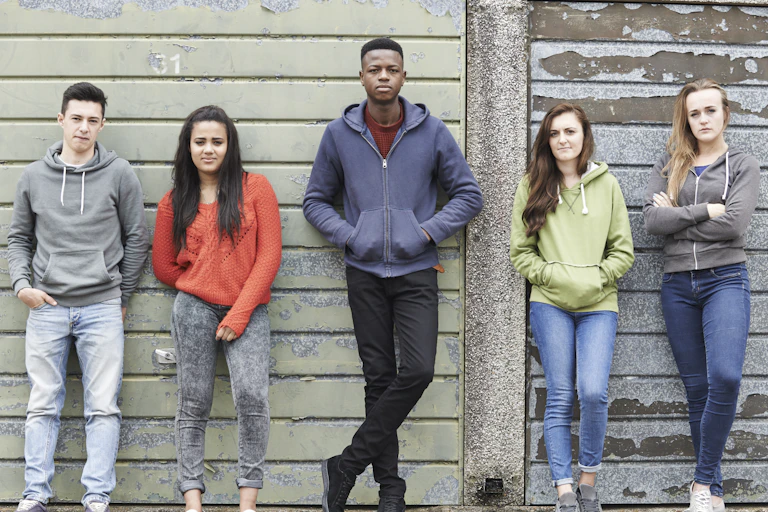 Group of young people leaning on a wall.