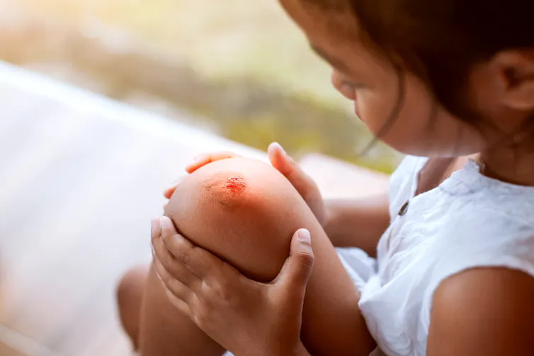 Une petite fille regarde son genou griffé