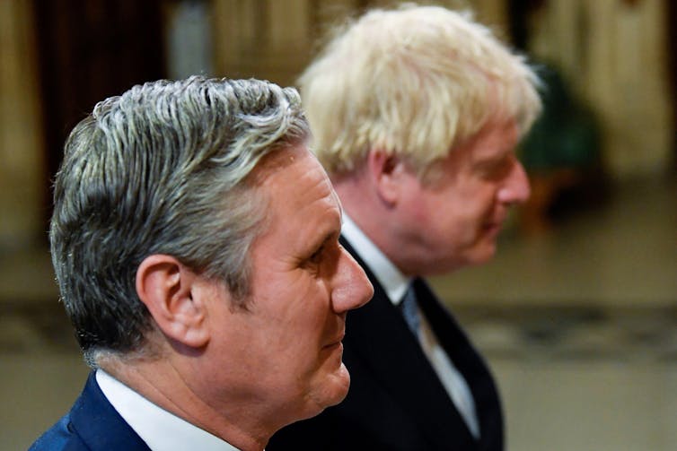 A close-up of the heads of Keir Starmer and Boris Johnson seen in profile in an indoor setting.