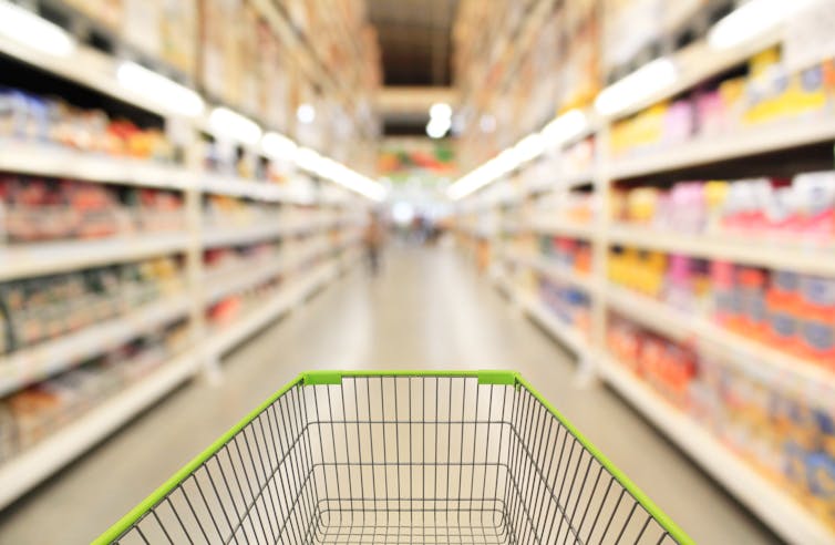 Shopping trolley in supermarket aisle.