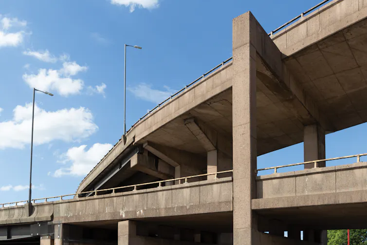 Intersecting and overlapping concrete structures seen against a blue sky.