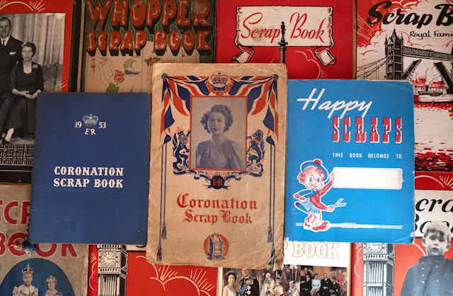 top-down view of an assortment of red, white and blue fronted scrapbooks. In the centre is a coronation scrapbook featuring a portrait of the young Queen Elizabeth II.