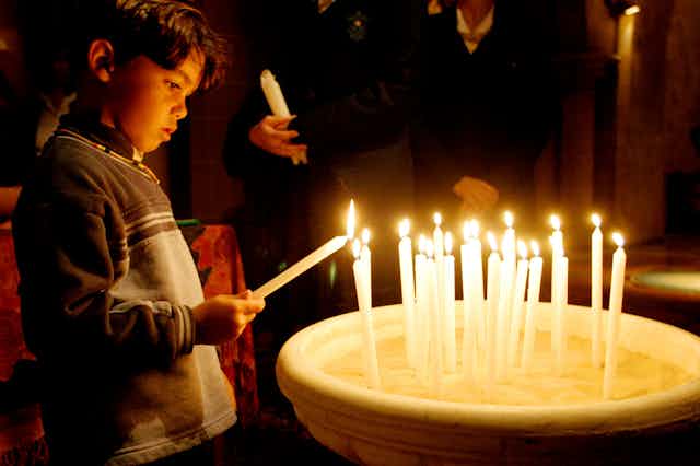 A young child lights a candle to commemorate the Stolen Generations.