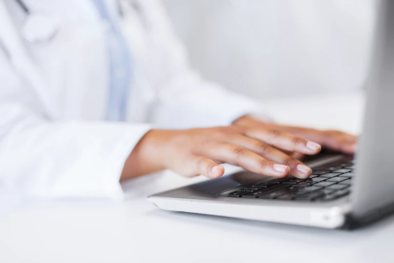 doctor types on laptop