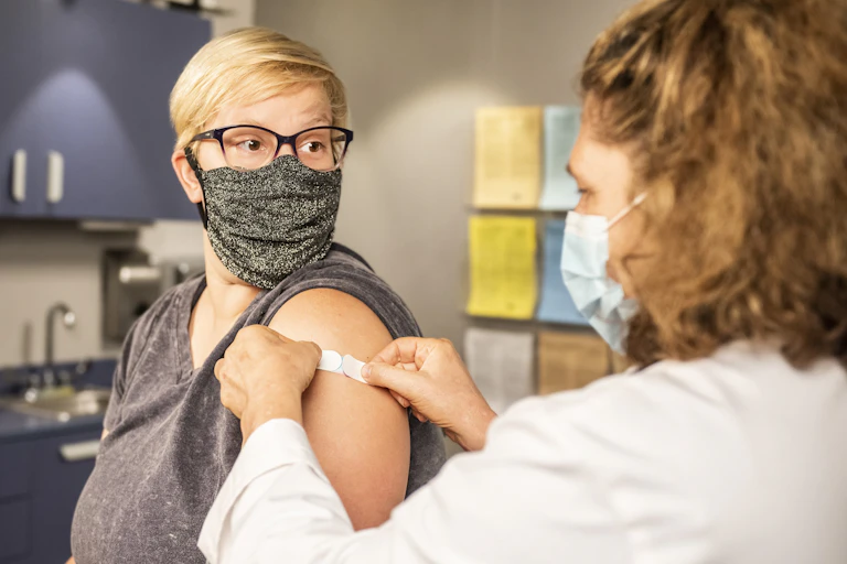 Nurse puts a bandaid on a patient's arm after a vaccination.