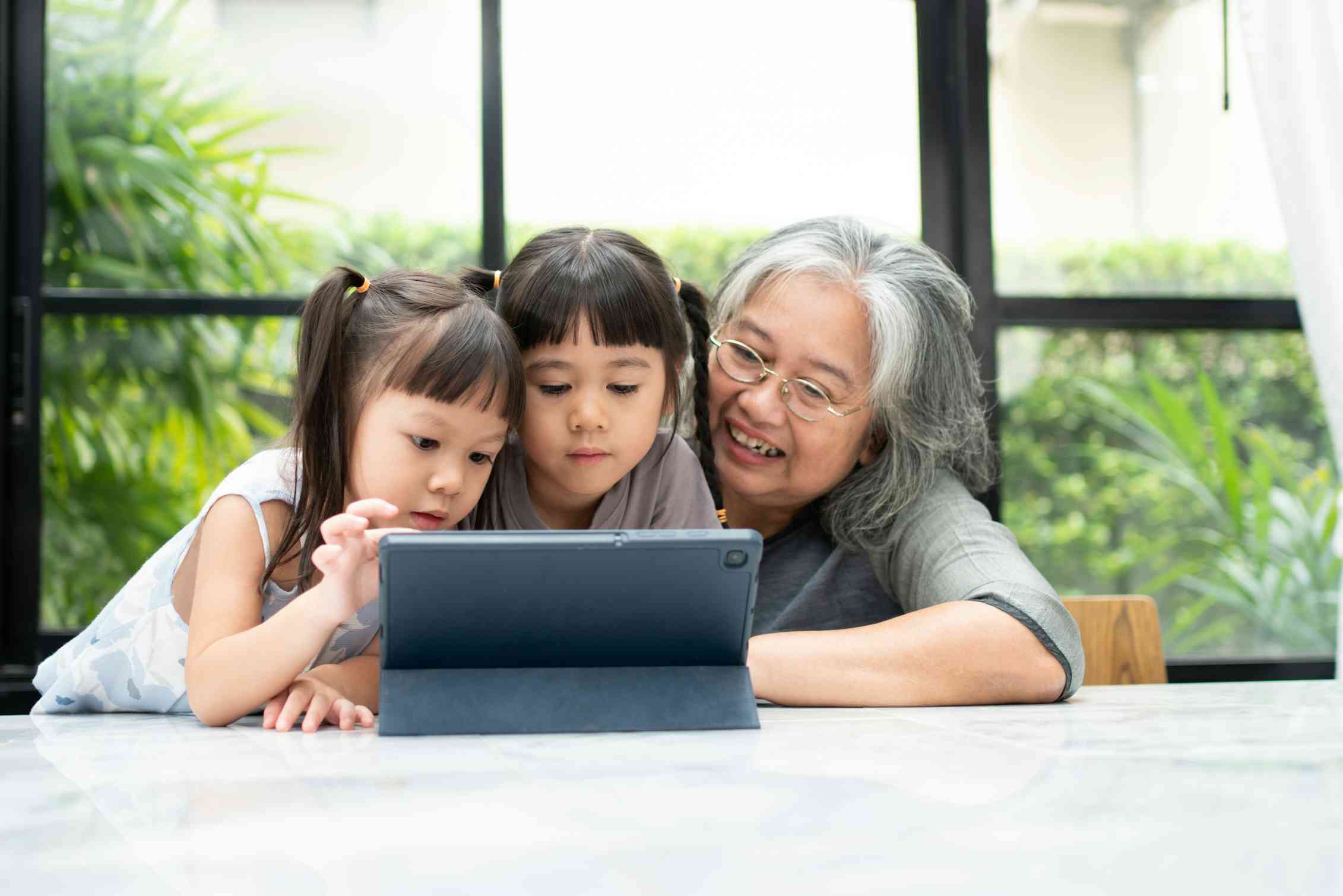 Grandmother and children playing on tablet