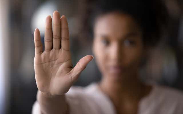 A woman holds up her hand, signaling 'stop.'