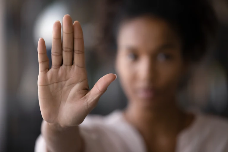 A woman holds up her hand, signaling 'stop.'