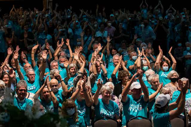 A crowd of cheering people wearing teal t-shirts