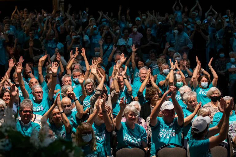 A crowd of cheering people wearing teal t-shirts