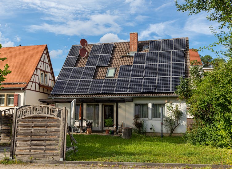 An old house with its roof covered in black solar panels