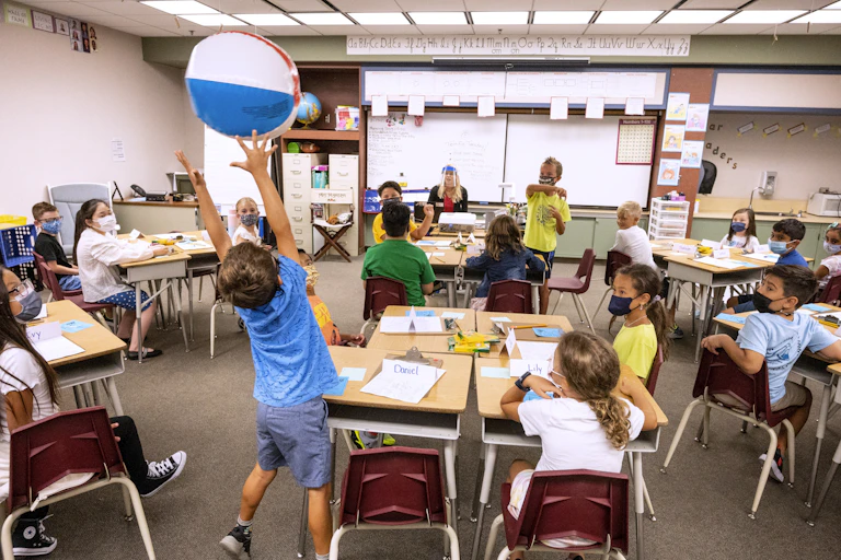 Students pass a beach ball around to the next person on the list during roll call