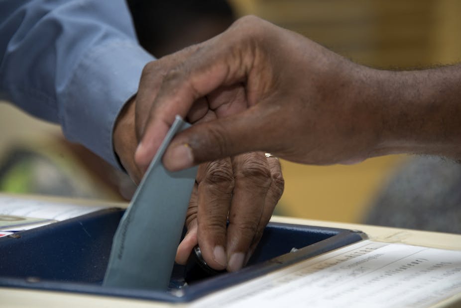 Un homme dépose son bulletin de vote lors du second tour des élections législatives françaises dans un bureau de vote à Pointe-a-Pitre, le 17 juin 2017.