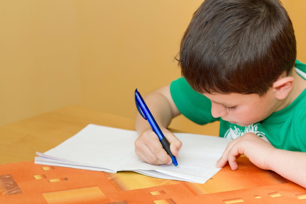 Делать уроки на английском. Писающий мальчик. Ребенок пишет в тетради. Ученик с ручкой в руке. Ребенок сочиняет.