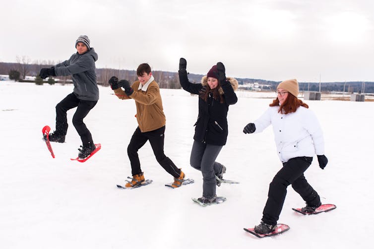 A group of youth are seen snowshoeing.