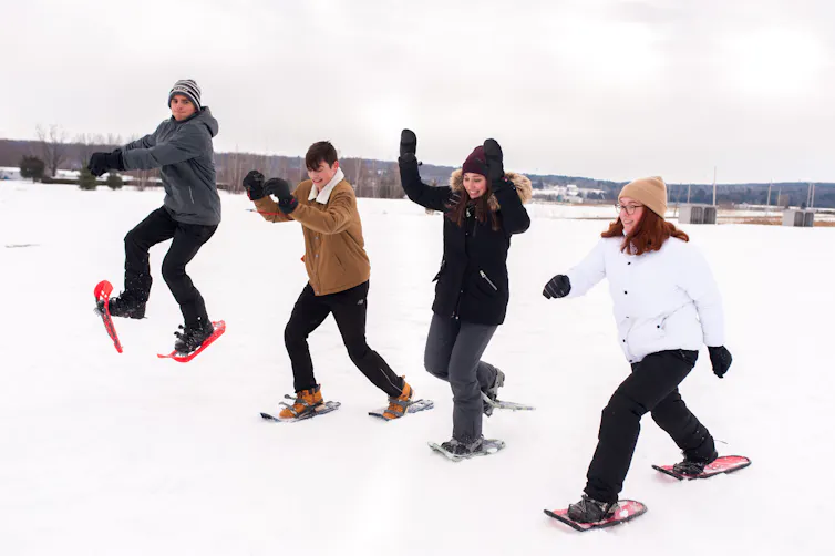 A group of youth are seen snowshoeing.