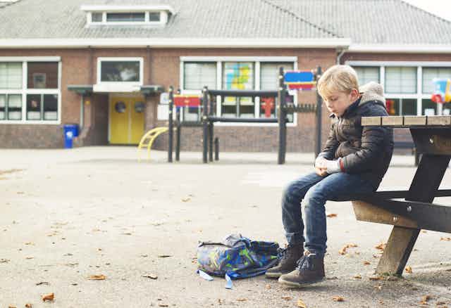 jeune garçon triste dans une cour d'école