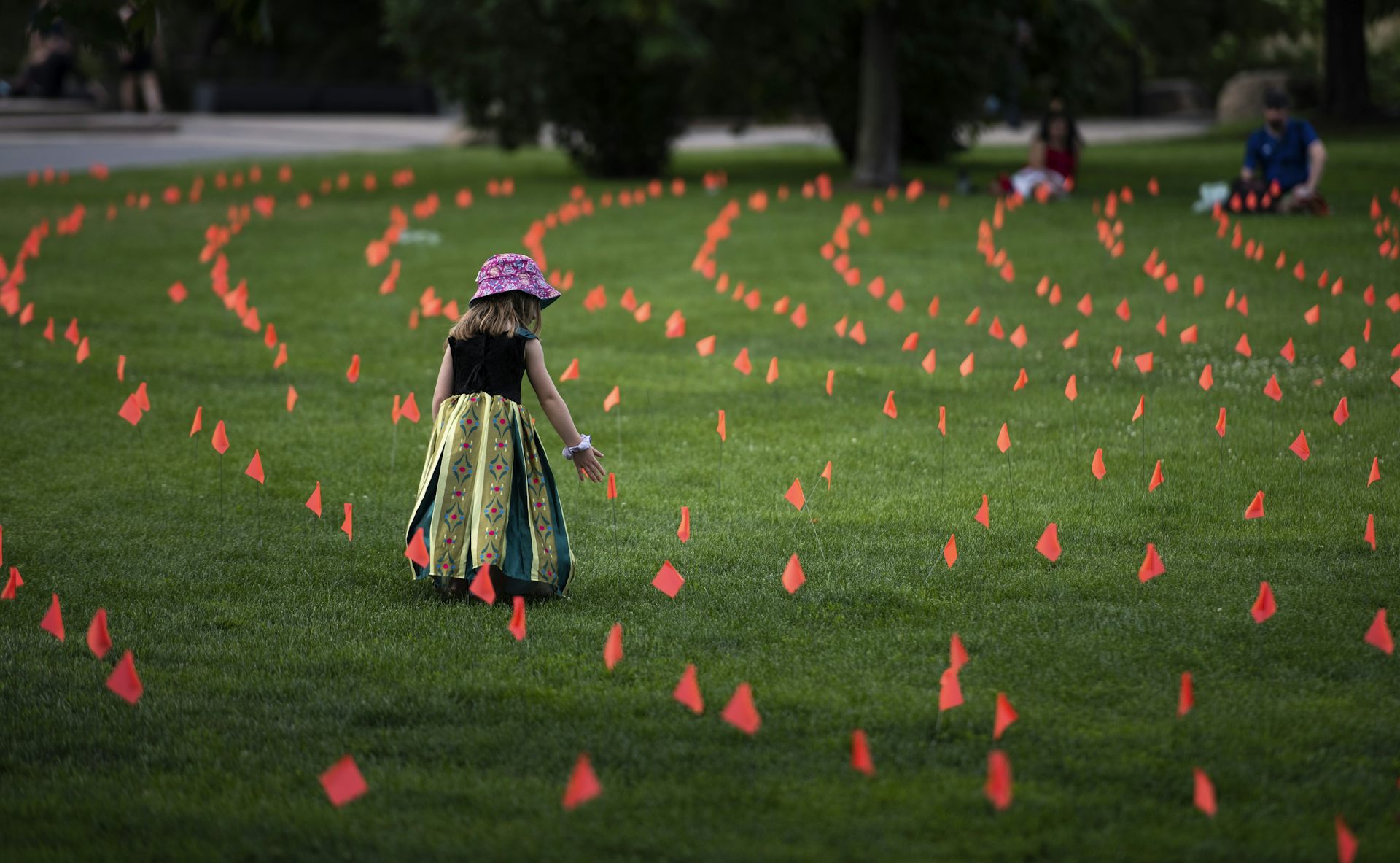A child stands amid hundreds of orange flags