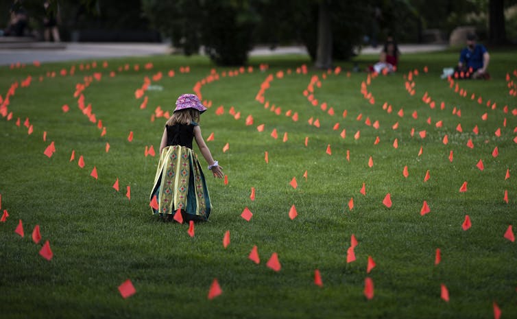 A child stands amid hundreds of orange flags