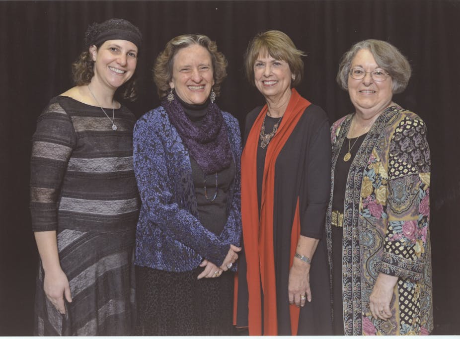 Four female rabbis in colorful dresses stand side by side.