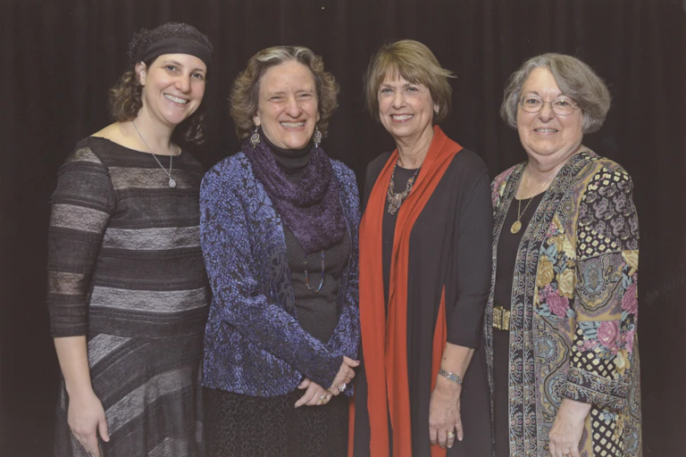 Four female rabbis in colorful dresses stand side by side.