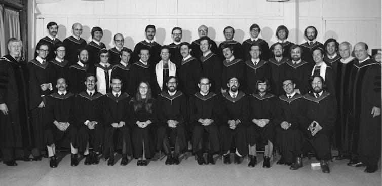 Students in black regalia seated along three rows for a class photograph.