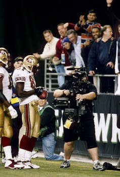 Football player signs ball in end zone.