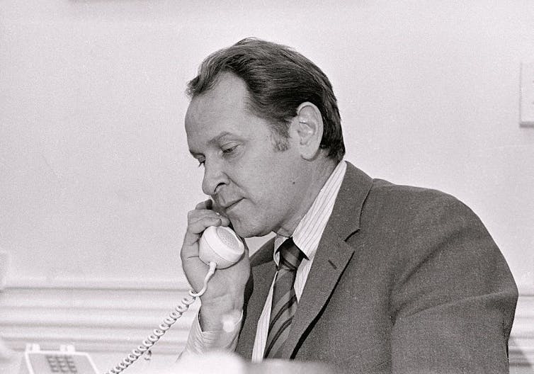 Man in suit talks on phone.