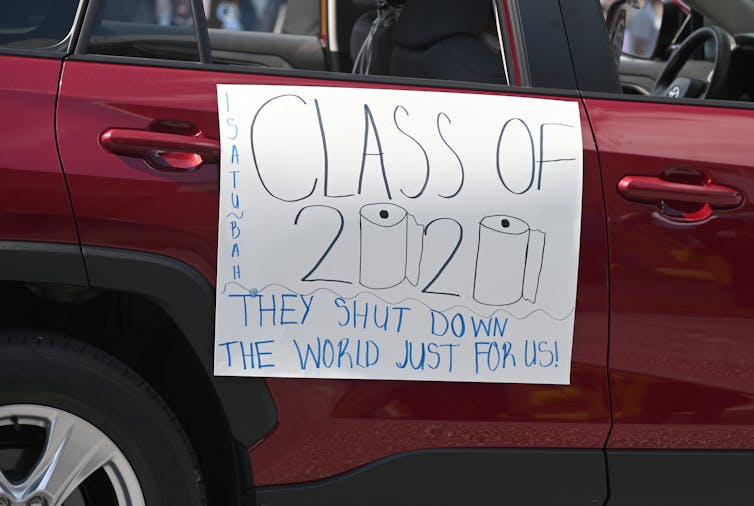 Maroon car with a Class of 2020 sign attached, with drawings of toilet paper rolls in place of the zeros.